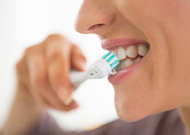 Profile nose-to-chin view of woman brushing her teeth
