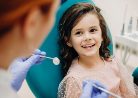 Girl in dental chair smiling at her dentist