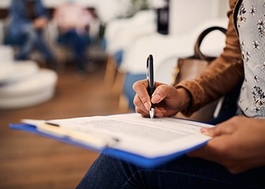 Hands filling out forms on a blue clipboard
