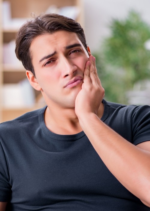 Man holding his cheek in pain needing emergency dentist in Cumming