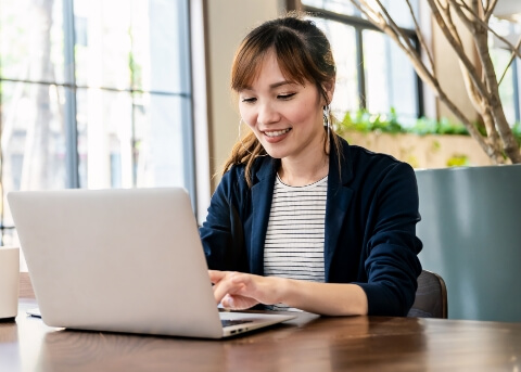 Woman sitting at table and typing on laptop