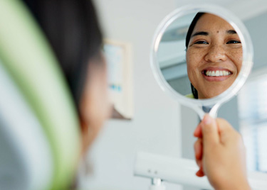 Woman smiling at reflection in dentist office