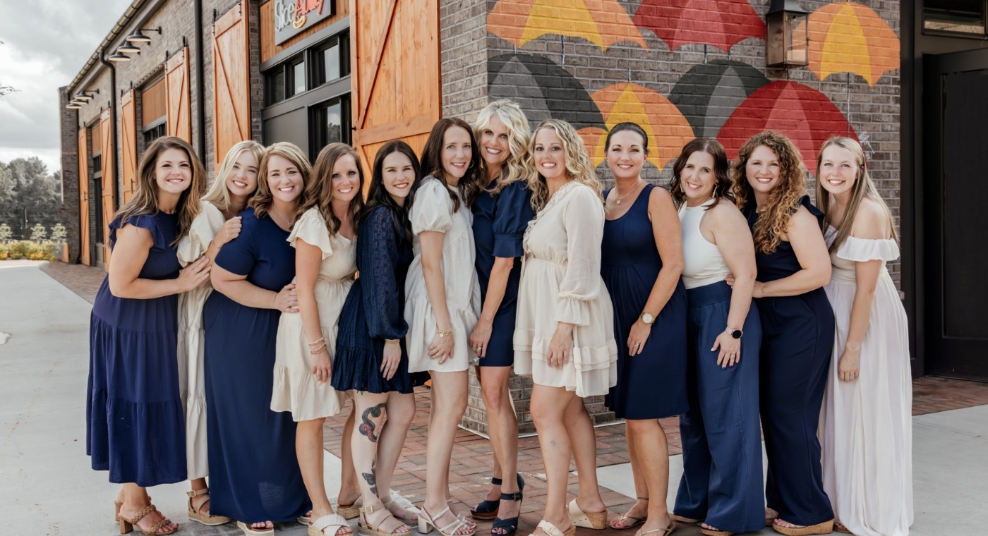 Dental team members in dark blue and tan dresses standing outside of Bragg Dental office in Cumming