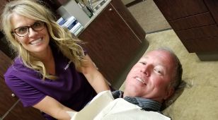 Doctor Bragg smiling next to a man in the dental chair