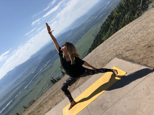 Doctor Bragg stretching on a yoga mat with green hills in background
