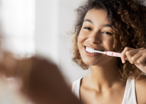 Woman smiling while brushing her teeth