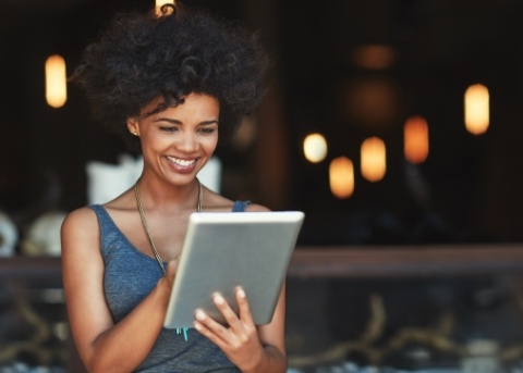 Woman smiling while scrolling on her tablet