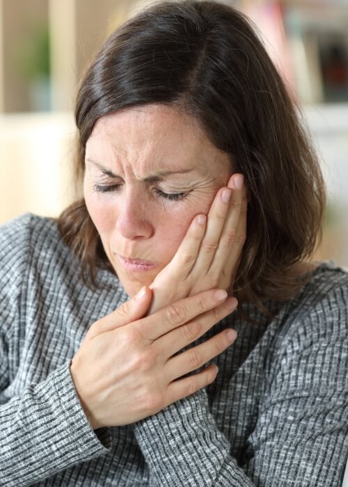 Woman holding her jaw in pain needing T M J treatment in Cumming
