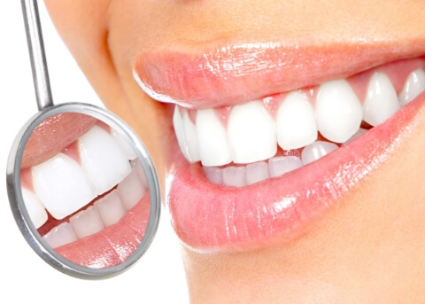 Close up of dental mirror reflecting smile with white teeth