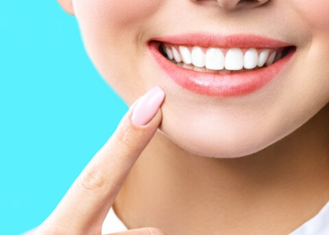 Close up of woman pointing to her smile